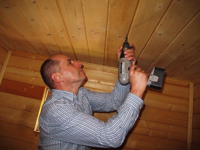 Сергей завинчивает саморез в потолок, чтобы подвесить датчик влажности и температуры.